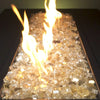 A close-up of Starfire Glass 1/2" Broken Gold Reflective Fire Glass (10lbs), shimmering with golden hues under an intense fire. Ideal for table fire pits, outdoor fire bowls, and fire tables for patios.