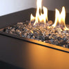 A freestanding fire pit table filled with Starfire Glass 1/2" Broken Gray Reflective Fire Glass (10lbs). The high-quality tempered fire glass provides stunning reflection and enhances fire pits outdoor, fire tables propane, and rectangular fire pits.