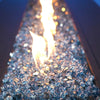 A breathtaking shot of Starfire Glass 1/2" Broken Fire Glass (10lbs) in Pacific Blue Reflective, arranged in a sleek, modern fire pit. The reflective crushed glass pieces shimmer under the flickering flames, making it an ideal choice for backyard fire pits, propane fire tables, and luxury fire bowls.