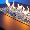 A close-up view of Starfire Glass 1/2" Broken Fire Glass (10lbs) in Pacific Blue Reflective, displaying a rich reflective surface with flames dancing over the premium crushed glass. The deep gray hue complements modern fire pits, outdoor gas fireplaces, and patio fire tables, creating a luxurious ambiance.