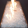 A high-quality close-up of Starfire Glass 1/2" Broken Fire Glass (10lbs) in Ultra Clear, perfectly arranged in a modern gas fire pit. The shimmering crushed fire glass enhances the flames, providing a bright, reflective glow that adds elegance to patio fire pits, fire bowls, and gas fire tables.