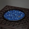 A sleek metal patio fire pit table featuring Starfire Glass Reflective Fire Drops in an eye-catching blue shade. The intricate woven metal design enhances the modern aesthetic, making it a great fit for an outdoor gas fire pit table, table fire pits, or a fire pit for backyard gatherings.
