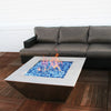 A contemporary outdoor fire pit table with Starfire Glass Reflective Fire Drops in a vibrant blue hue, creating a dazzling flame effect. The modern stainless steel square design enhances the ambiance, making it a perfect addition to a backyard fire pit or outdoor gas fire pit setup. The fire glass offers improved heat reflection and long-lasting durability.
