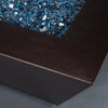 A detailed close-up of the corner of the Starfire Designs Steel Mill 60" x 32" Rectangle Gas Fire Pit in a copper vein finish, showcasing the sleek edge with blue fire glass. This high-quality fire pit is ideal for outdoor settings and offers a durable and stylish design. Key features include rust resistance, modern aesthetics, and a robust steel construction.