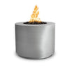 This image displays The Outdoor Plus 36" Beverly Steel Gas Fire Pit in stainless steel finish, featuring a cylindrical design with a smooth, brushed metal surface. The fire pit is shown with flames burning over black lava rocks, providing a sleek and modern look for outdoor living spaces. Ideal for use as a gas fire pit, this stainless steel model offers durability and contemporary aesthetics, making it perfect for patio or backyard setups.