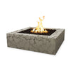 The Outdoor Plus 36" Quad Concrete Gas Fire Pit in moss stone, offering a rustic square design with textured concrete and a wide fire basin filled with dark lava rocks. The moss stone finish complements natural outdoor settings, blending seamlessly with garden or patio environments. Ideal for creating a warm and inviting atmosphere.