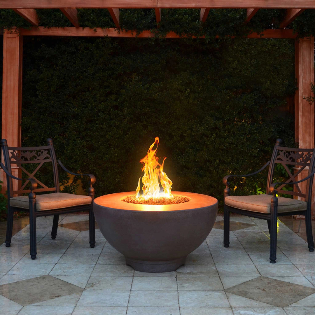 The Outdoor Plus 37-inch Sienna concrete gas fire pit displayed on a modern outdoor patio setting. The fire pit features a smooth round concrete design with a central gas burner, ideal for enhancing a backyard or garden environment. The flame dances over a bed of fire media, creating a warm and inviting ambiance. 