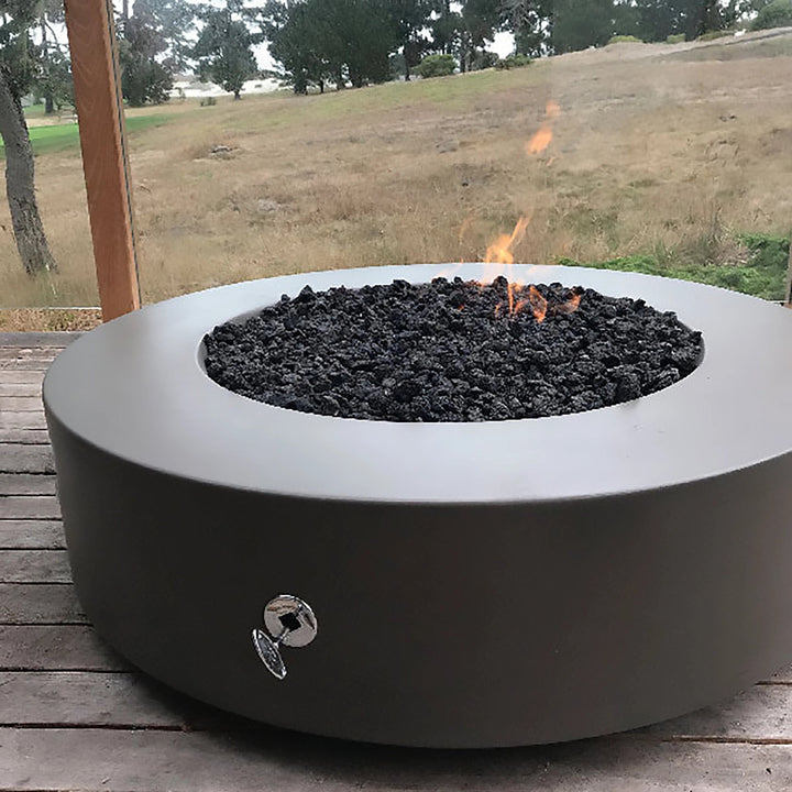 The Outdoor Plus 42-inch Occasional Height Florence Concrete Gas Fire Pit with decorative metal spheres placed atop black lava rocks. This stylish fire pit adds a modern touch to any patio, featuring a durable, textured concrete surface and wide burner area, suitable for propane or natural gas