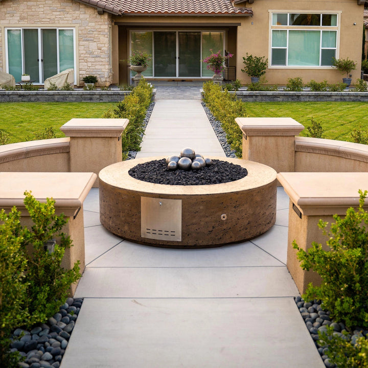 The Outdoor Plus 42-inch Occasional Height Florence Concrete Gas Fire Pit placed in a landscaped garden, offering a stylish and functional heating solution for outdoor spaces. Featuring a natural concrete finish and modern round design, this fire pit is compatible with both natural gas and propane fuel options