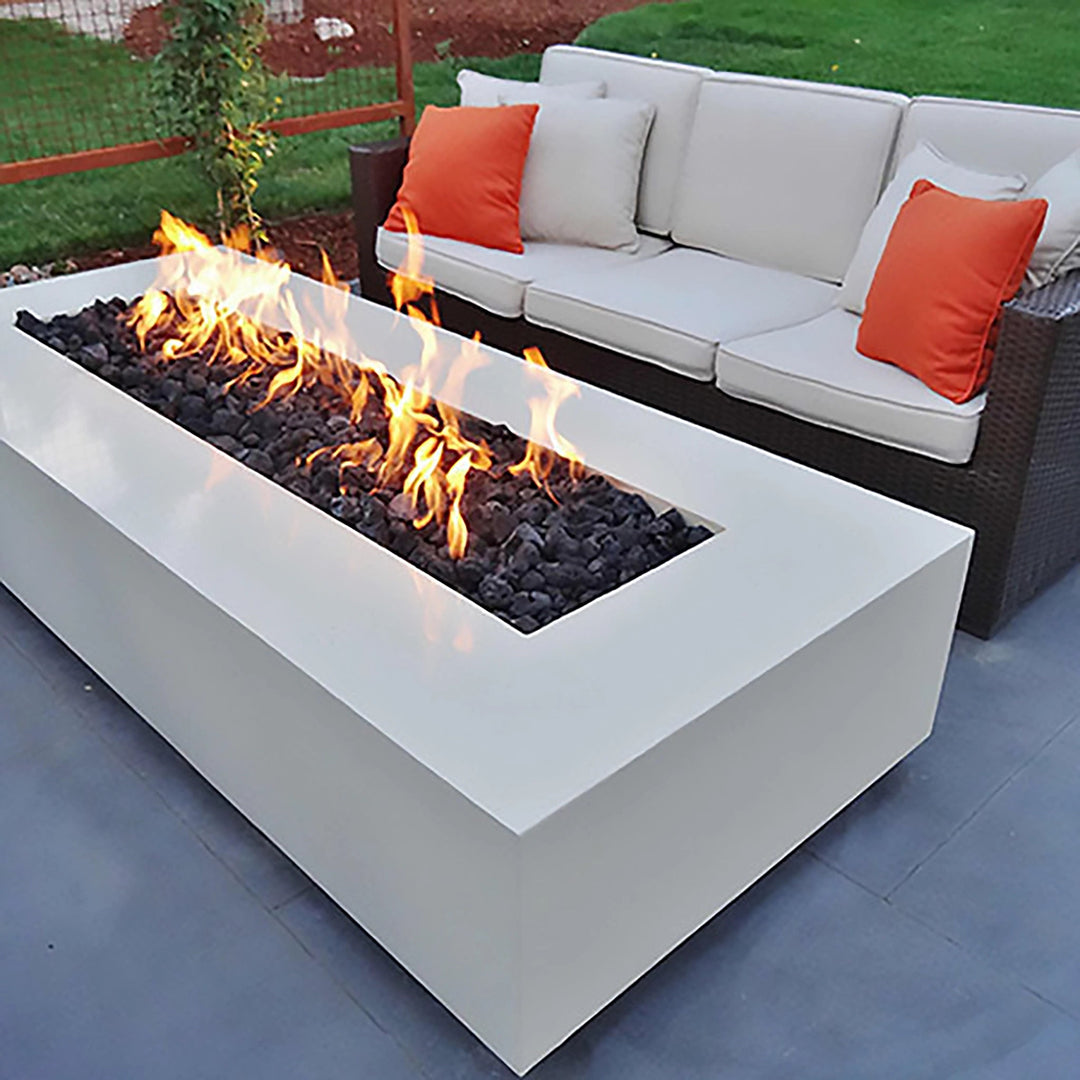 Patio setup featuring The Outdoor Plus 48" Coronado Steel Gas Fire Pit, paired with a comfortable seating arrangement. The fire pit's clean lines and robust steel build make it a stunning centerpiece for the patio, providing both warmth and a modern aesthetic. The flames dance over black lava rocks, enhancing the visual appeal of the setting. Ideal for both casual gatherings and formal outdoor entertaining.