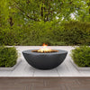 The Outdoor Plus 48" Sedona Wide Ledge Concrete Gas Fire Pit in black, featured in a lush garden setting. This fire pit is crafted from high-quality concrete, offering a sleek design with a wide ledge, perfect for enhancing any modern outdoor space. The black color contrasts beautifully with the greenery, making it an elegant addition to patios, terraces, or backyard areas. Ideal for creating a cozy ambiance in luxurious outdoor settings