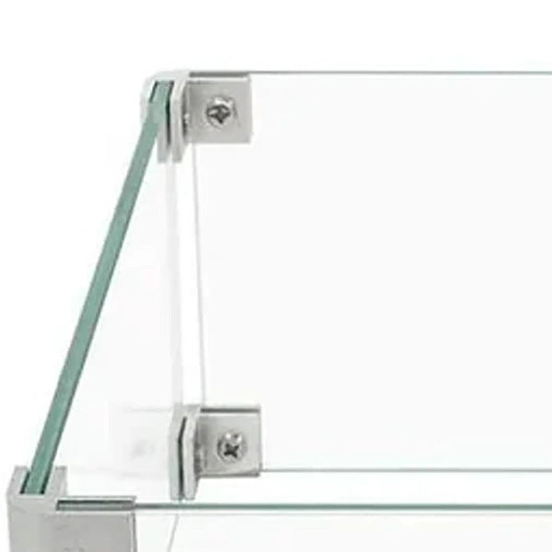Close-up view of The Outdoor Plus 20"x20" Square Tempered Glass Wind Guard corner, featuring polished glass edges secured with stainless steel brackets for outdoor fire pit protection. Ideal for safeguarding flames from wind while adding a sleek, modern touch to outdoor fire pit settings. Durable tempered glass with premium finish.