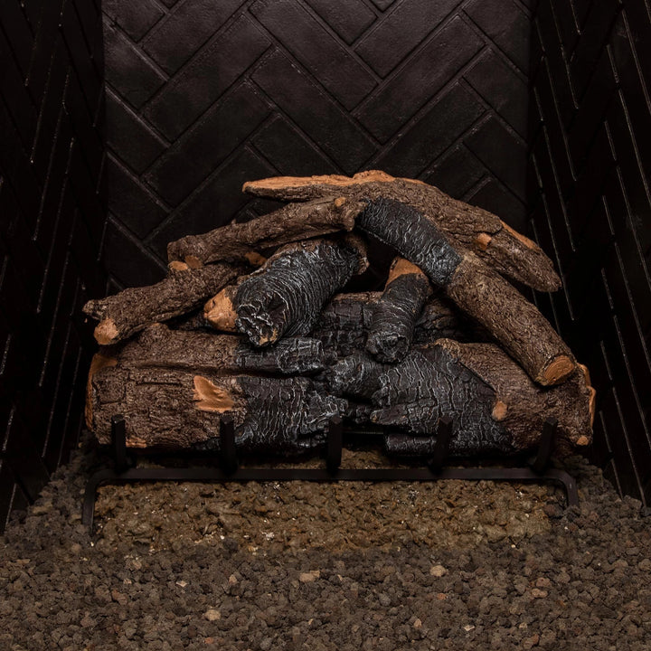 Stacked 24-inch Real Fyre Vented Charred American Oak Gas Logs in a fireplace grate without flames, highlighting the detailed bark and charred textures. This natural gas log set provides a realistic wood-like appearance in traditional fireplaces.